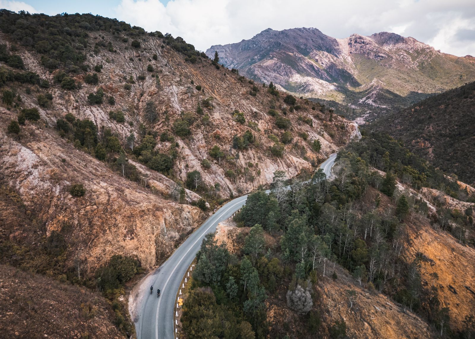 Drone shot of two bikepackers on the 99 bends road out of Queenstown, Tasmania