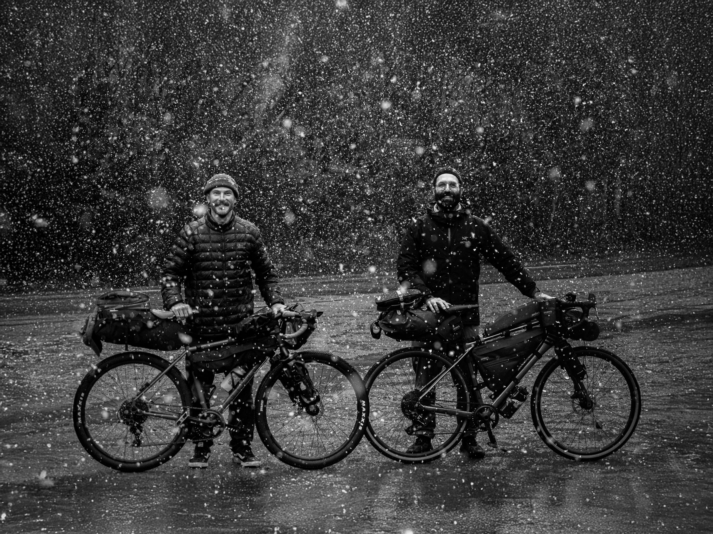 Justin Bumpstead and Mitch Wood with their loaded bikes in the snow at Derwent Bridge, Tasmania